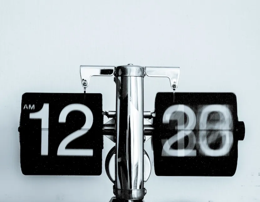 A flip clock showing 12:20 AM, the minute cards blurred mid-flip.